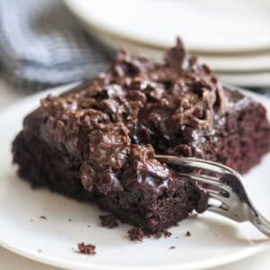 Taking a bite of a piece of chocolate crunch cake.