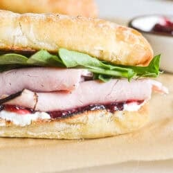 a side view of a ham and jam sandwich on a baguette.