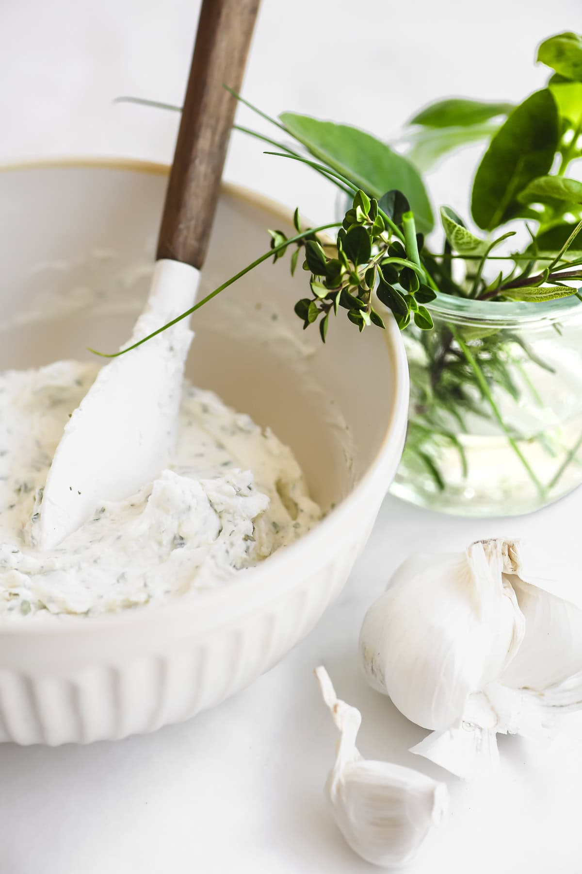 making homemade Boursin cheese in a small bowl, with garlic and herbs.