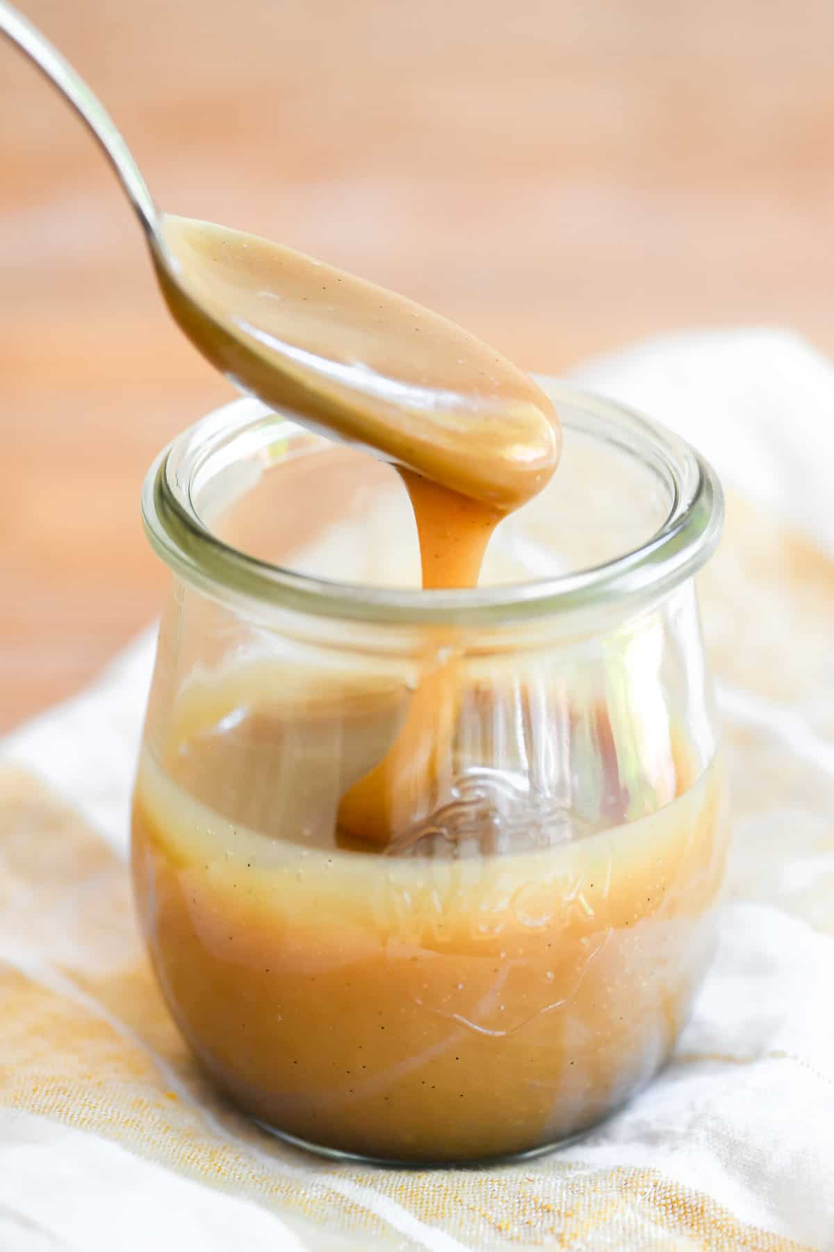 Spooning thick homemade butterscotch sauce from a small Weck tulip jar.
