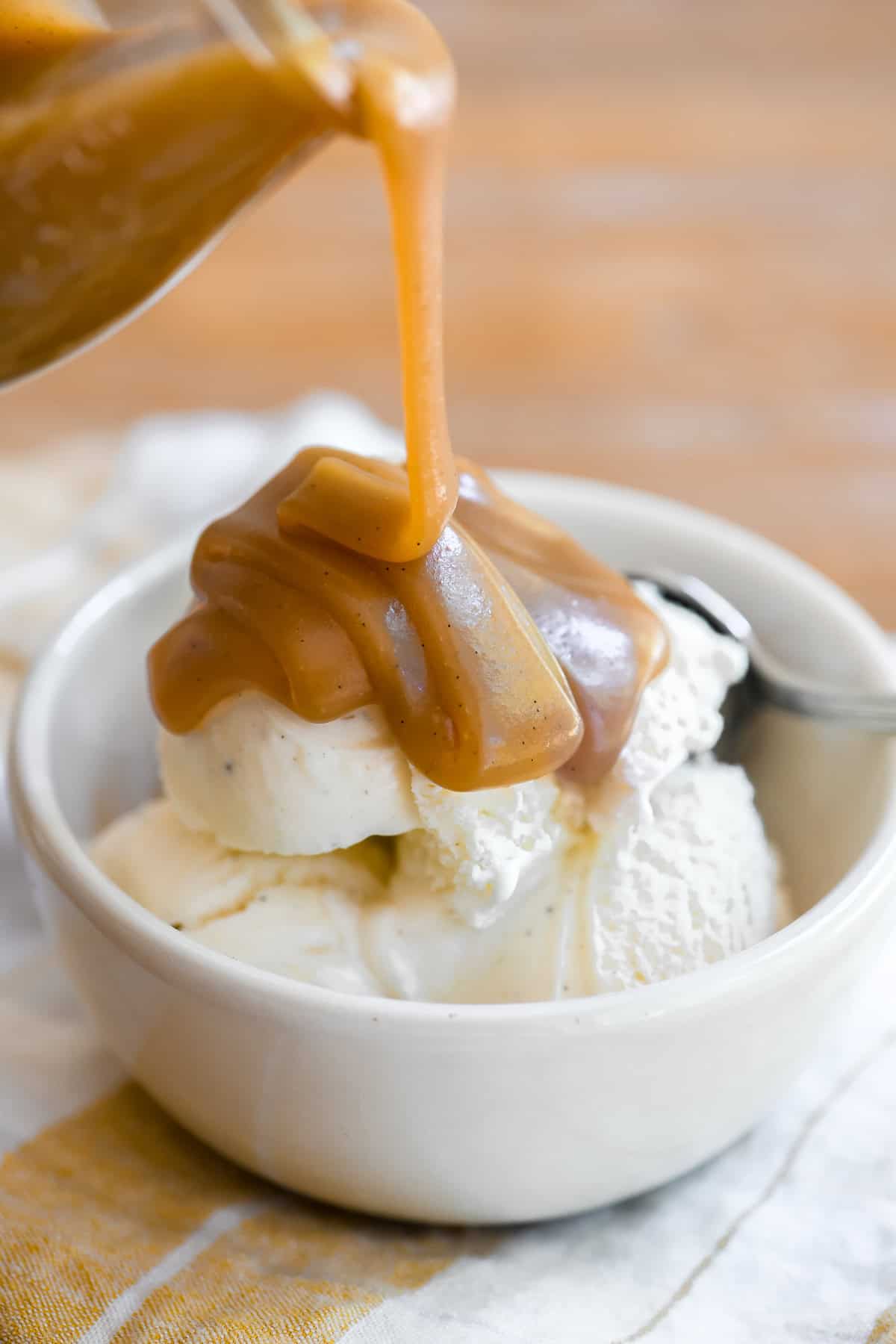 drizzling thick homemade butterscotch sauce onto a bowl of ice cream.