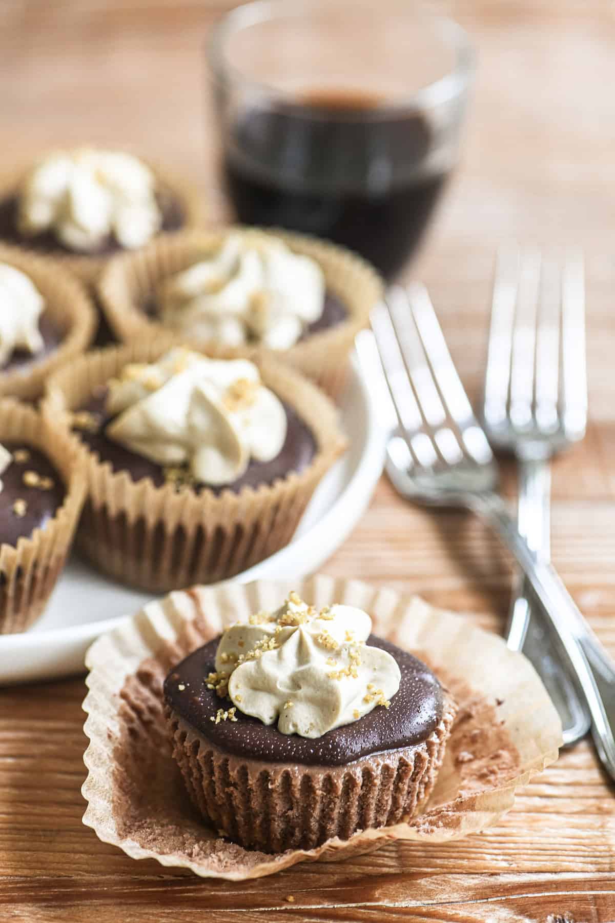 Mini mocha cheesecake topped with coffee whipped cream, with cupcake paper liner unwrapped.