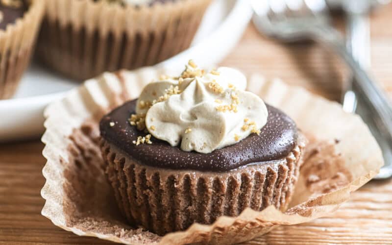 mini mocha cheesecake topped with coffee whipped cream, with paper liner peeled away.