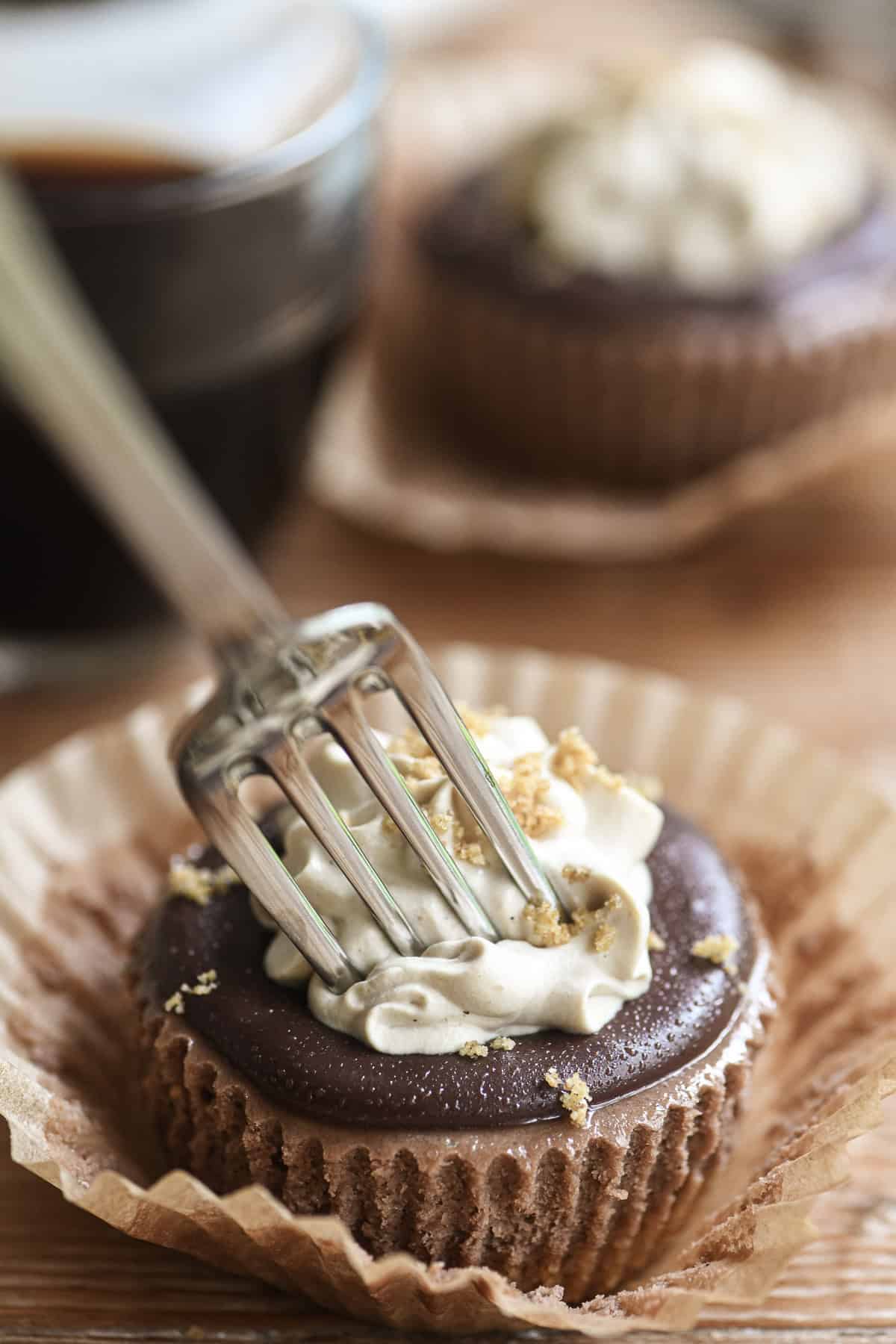 Plunging a fork into a mini mocha cheesecake.