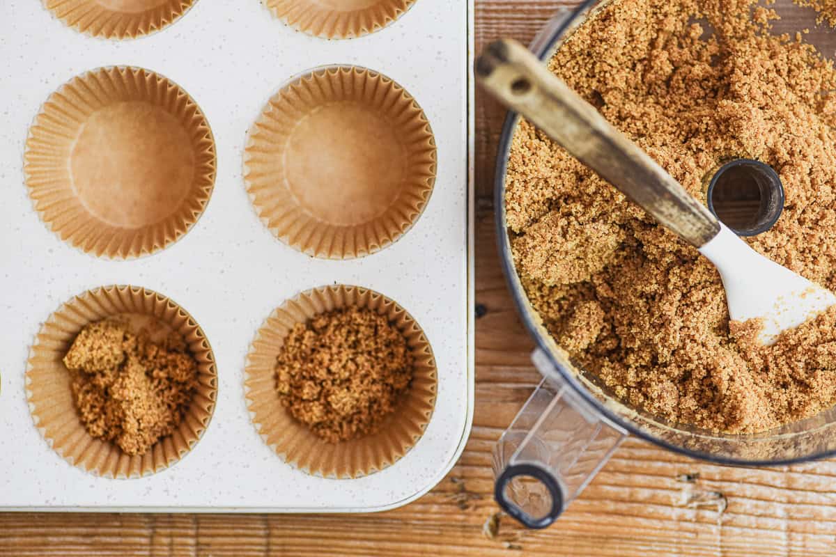 Pressing crust into muffin liners for mini mocha cheesecakes.