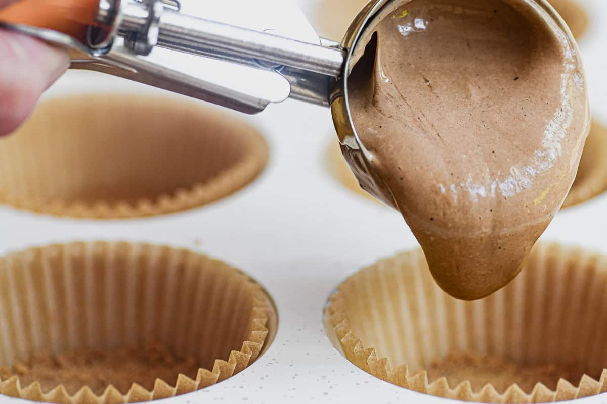 Scooping mocha cheesecake batter into muffin cups.