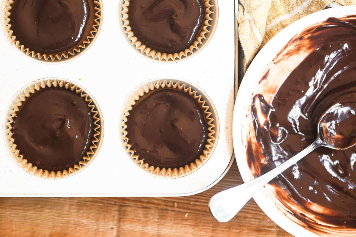 layering ganche over mini mocha cheesecakes.