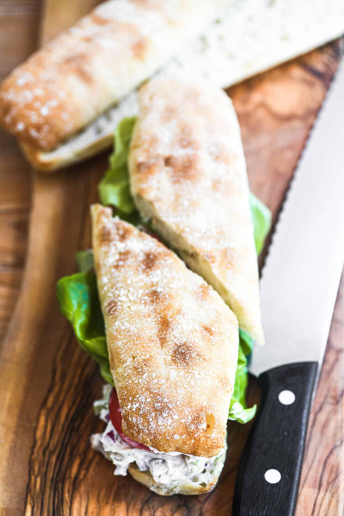 Slicing a smoked trout salad sandwich in half.