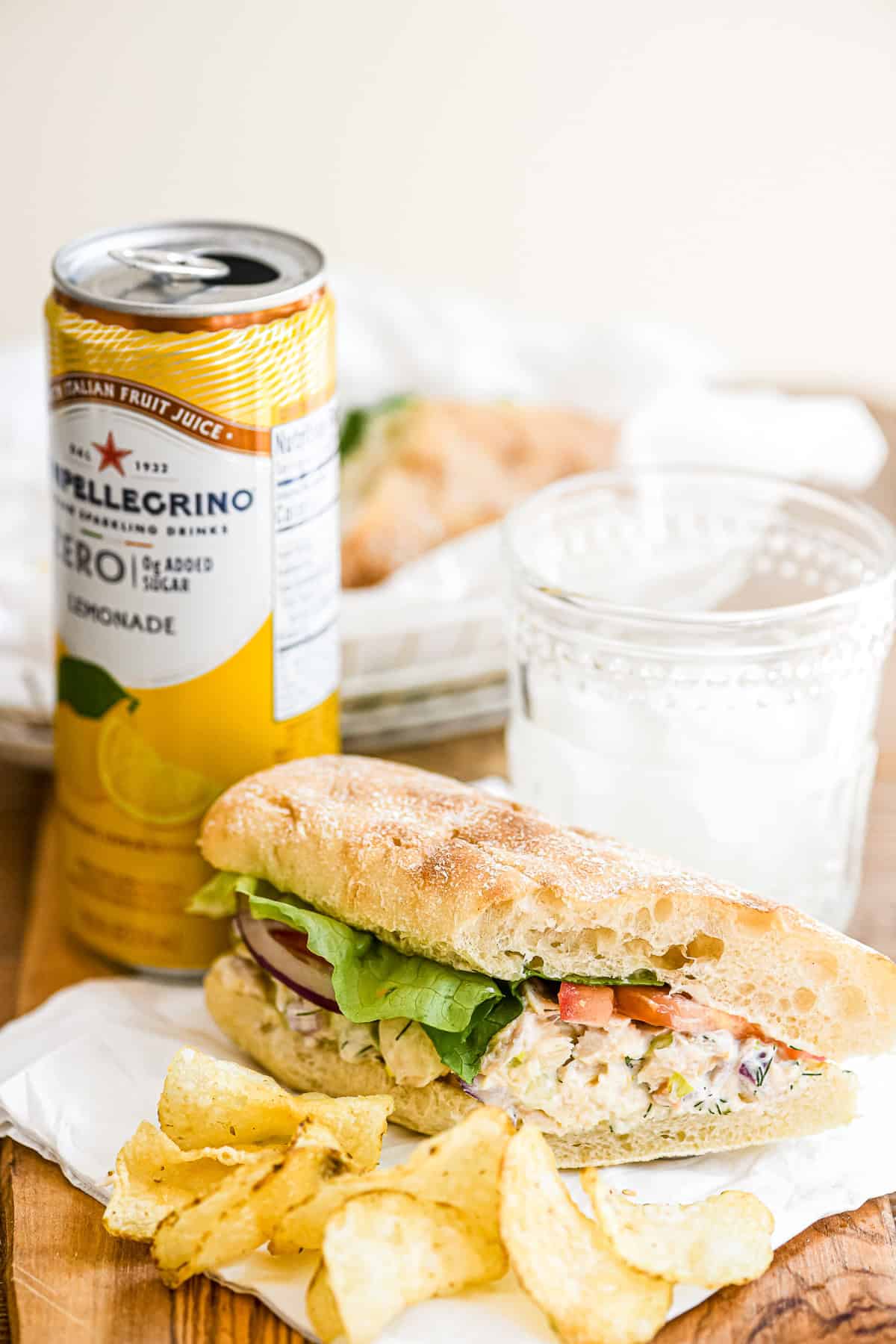 a smoked trout salad sandwich on a board with potato chips