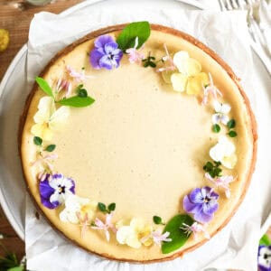 spring vanilla bean cheesecake decorated with a wreath of delicate spring edible flowers.