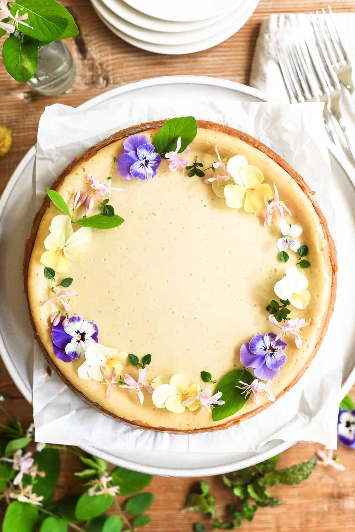 spring vanilla bean cheesecake decorated with a wreath of delicate spring edible flowers.