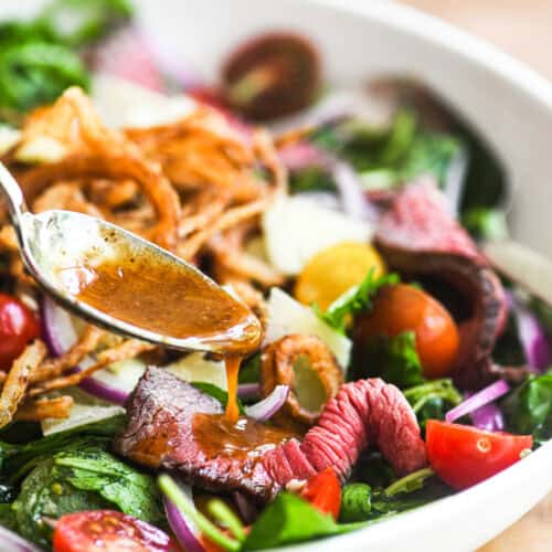 Spooning A1 vinaigrette onto a steak salad.