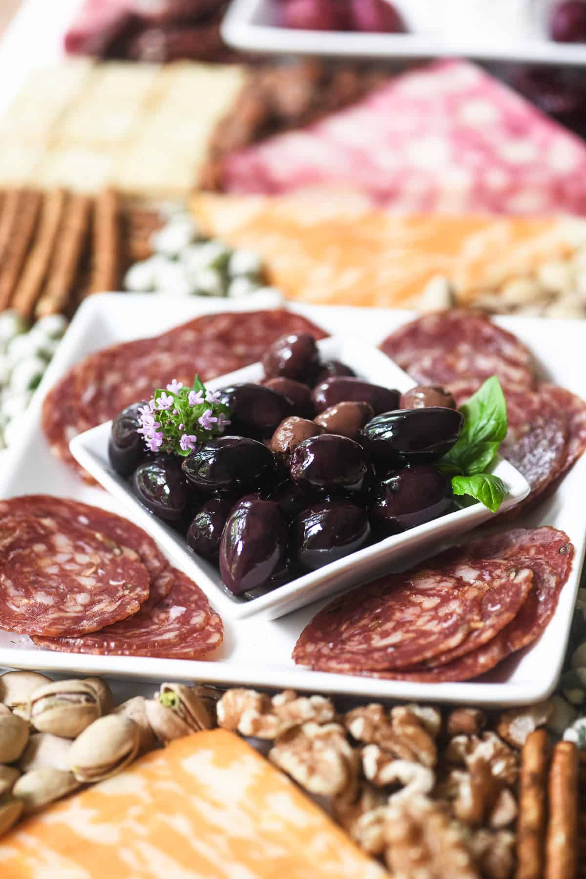 Classic charcuterie ingredients arranged in a quilt pattern on a charcuterie board.