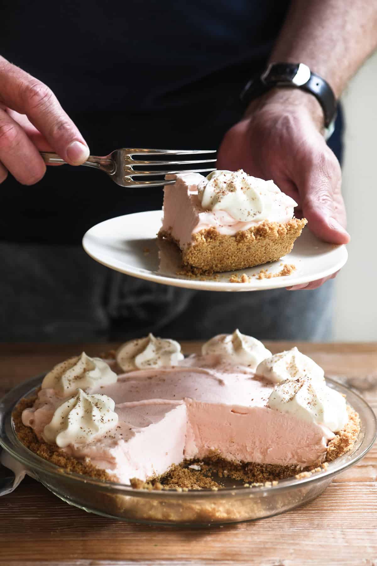 Holding a piece of Frozen Pink Squirrel Pie and taking a bite.