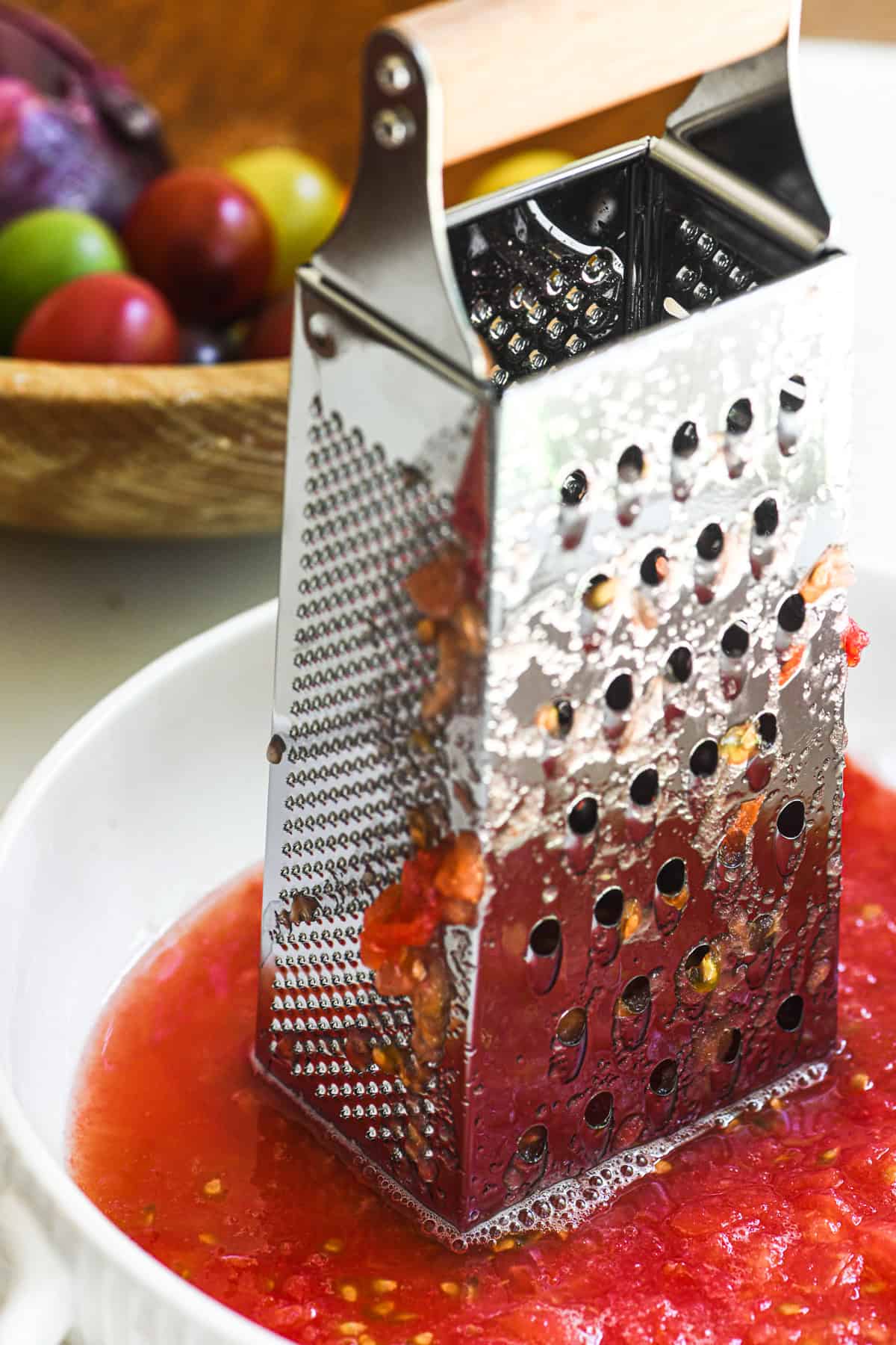 A box grater with tomato sauce in a bowl.