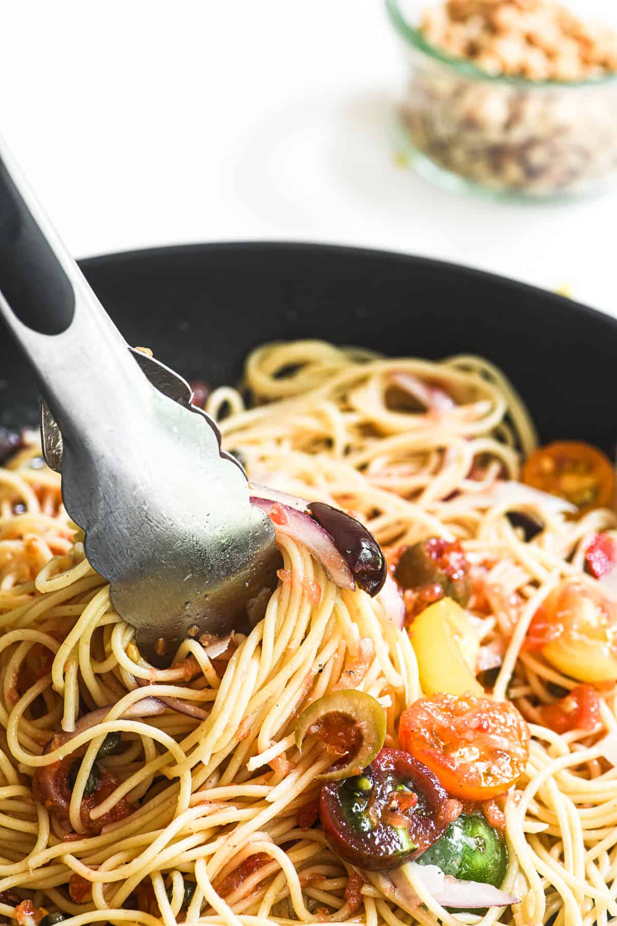 Tossing a no-cook Mediterranean pasta sauce with thin spaghetti.