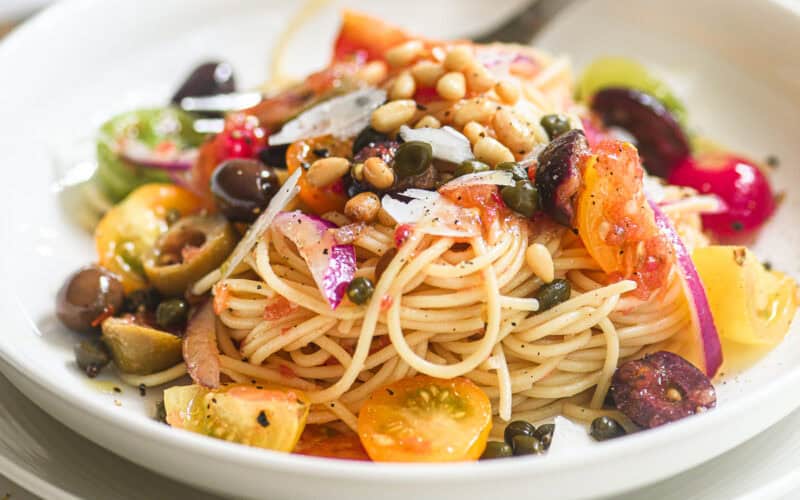 A bowl of spaghetti with no-cook Mediterranean pasta sauce.