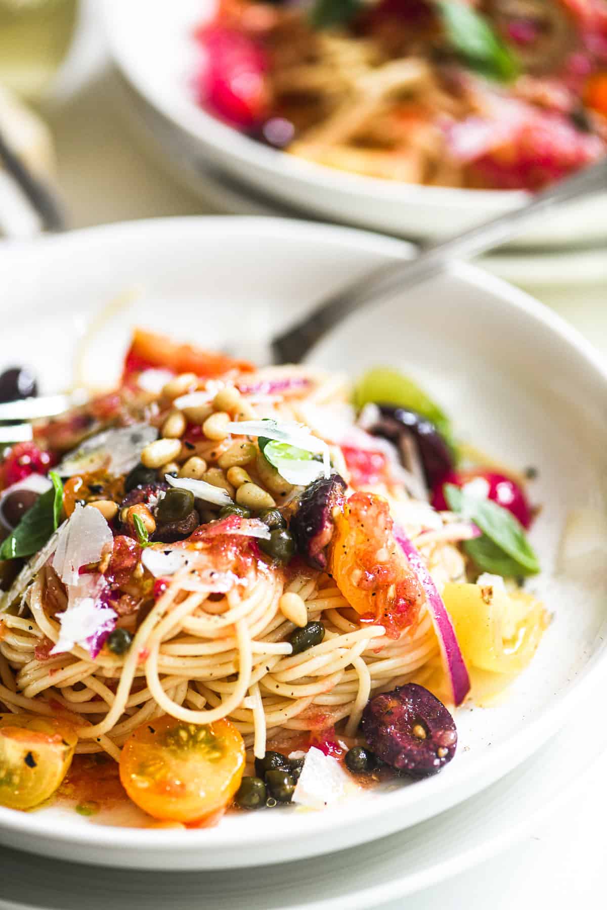 Spaghetti with no cook Mediterranean pasta sauce, in shallow white bowls.