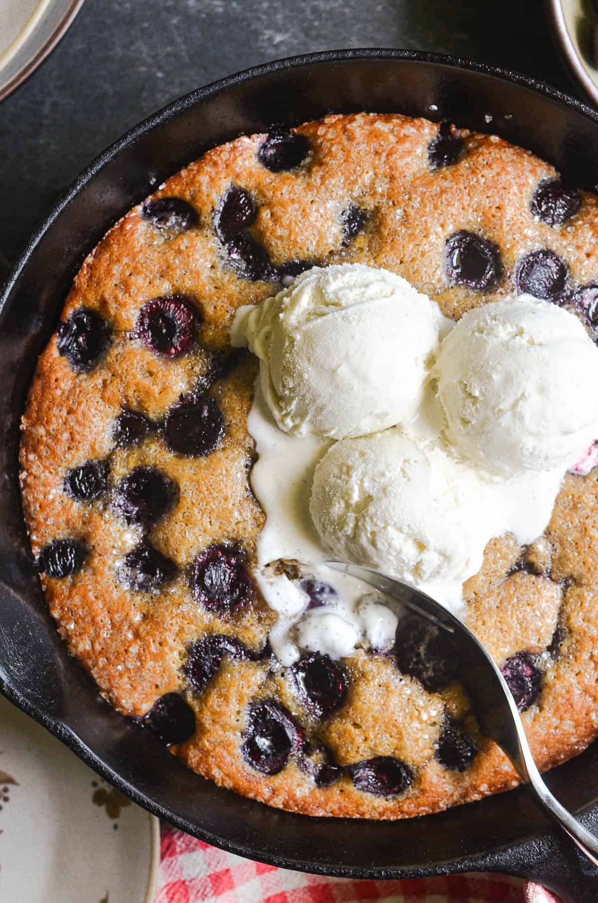 Cherry almond skillet cake topped with vanilla ice cream.