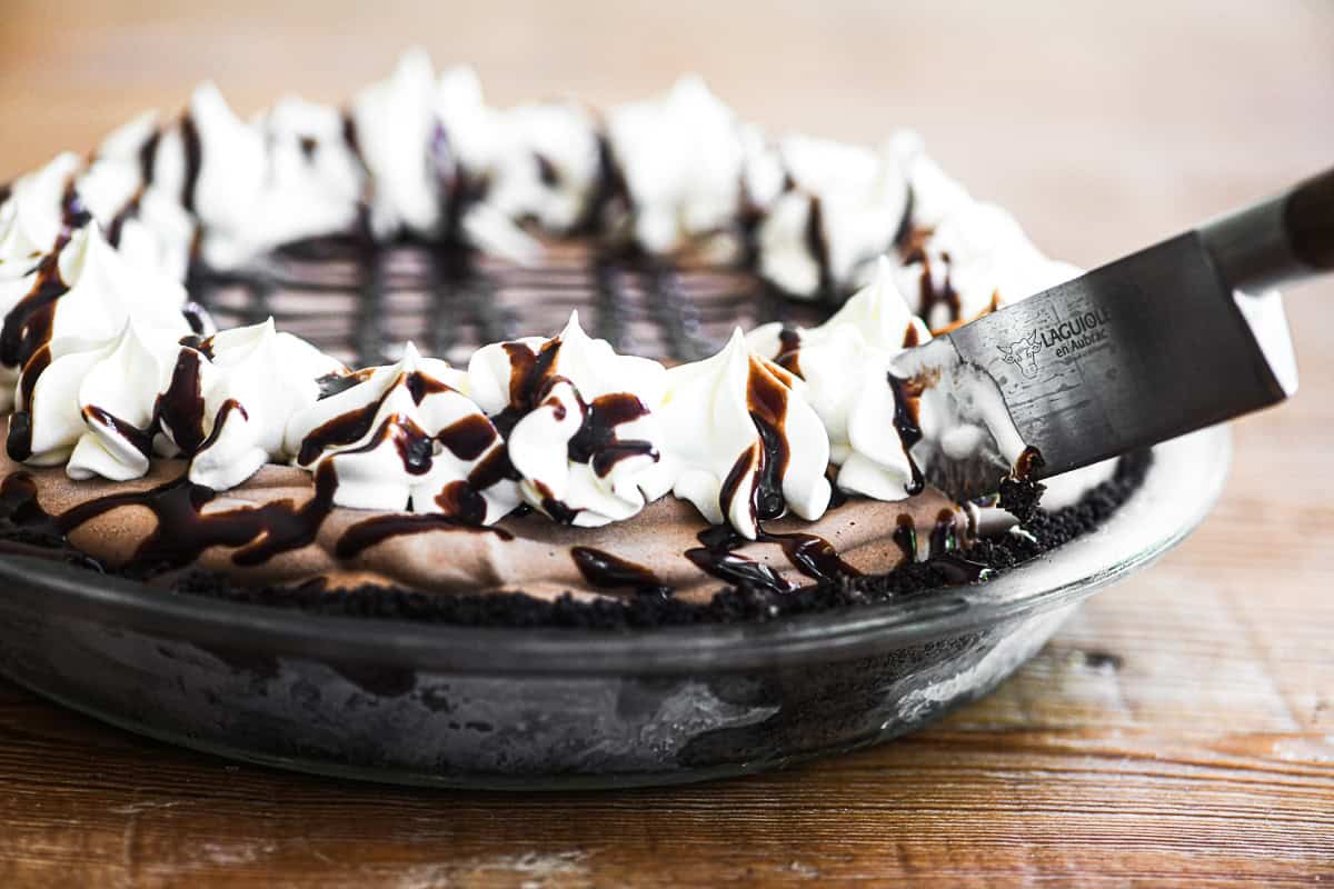 Slicing into a frozen mudslide pie with a sharp knife.