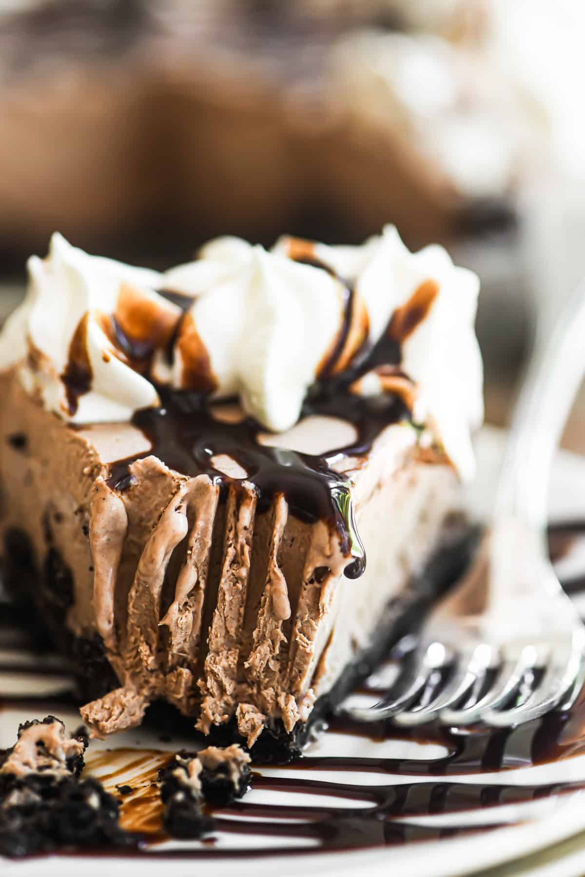 A slice of frozen mudslide pie with fork marks and dripping chocolate glaze.
