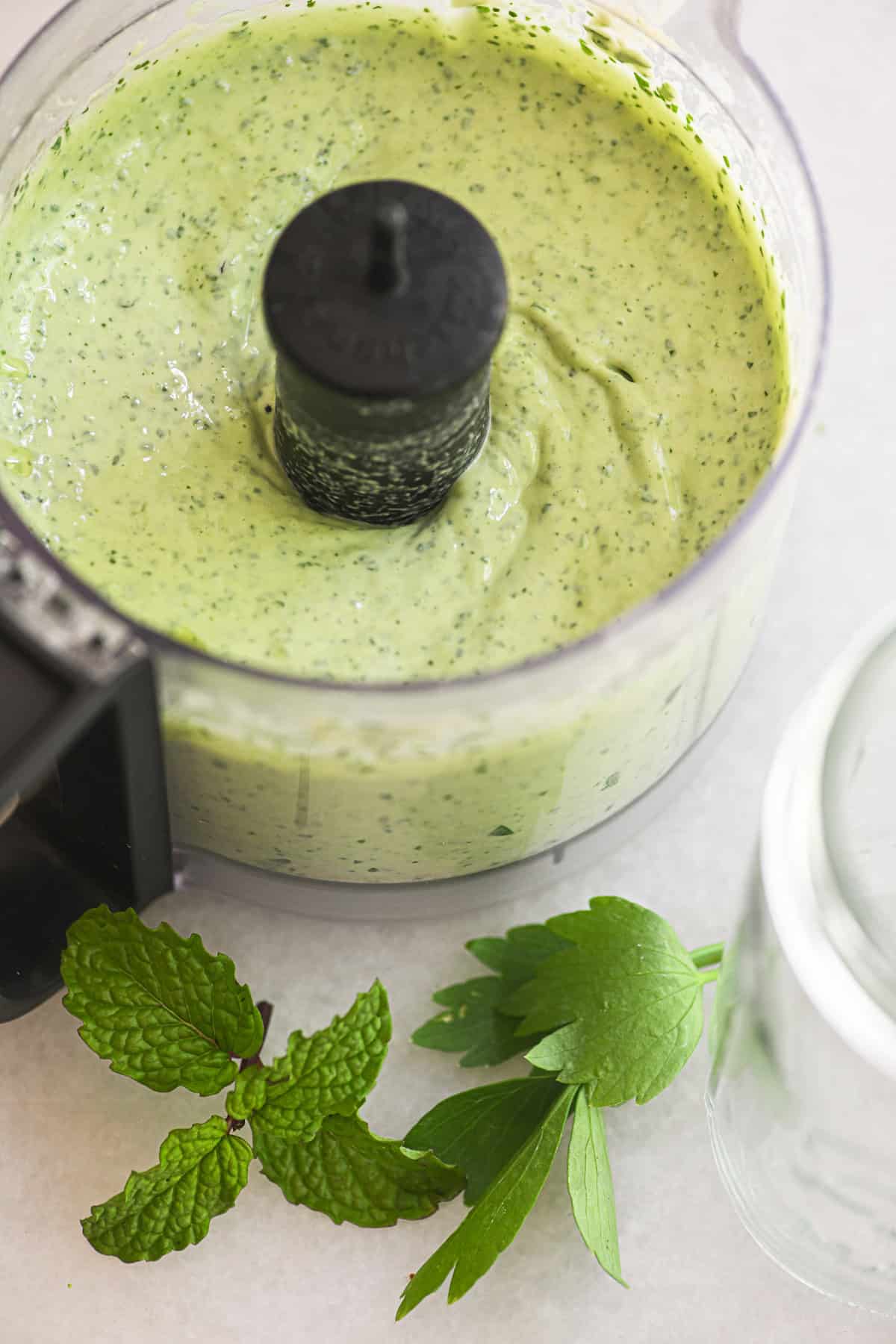 Making green tahini sauce in a small food processor.