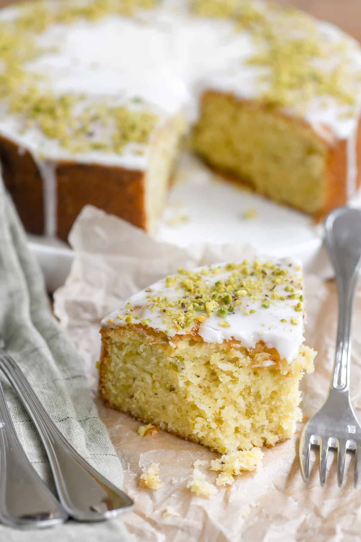 A slice of lemon pistachio cake with bite taken.