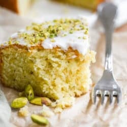 A slice of lemon pistachio cake with bite taken.