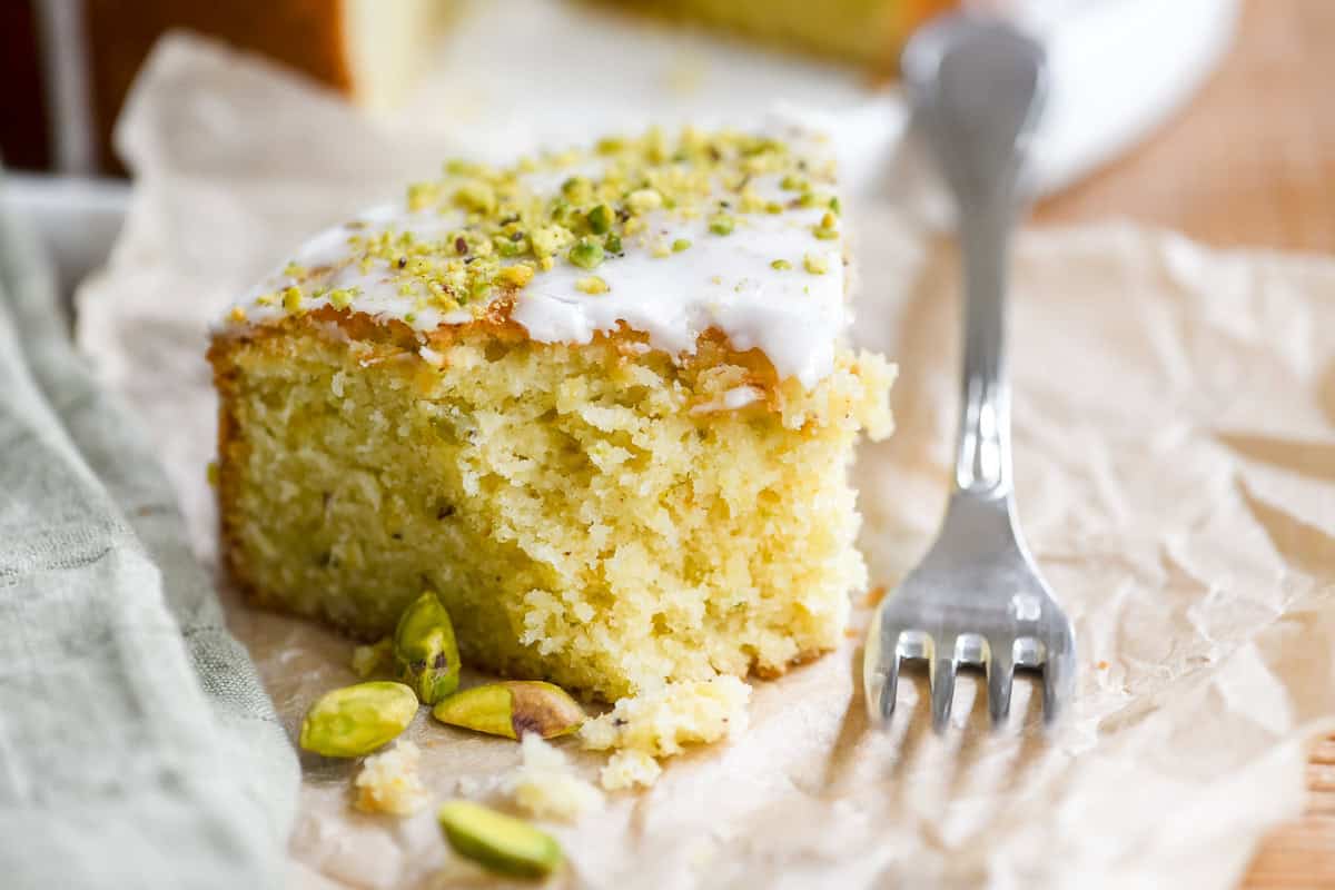A slice of lemon pistachio cake with bite taken.