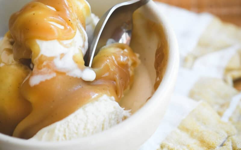 Butterscotch sauce on vanilla ice cream, with spoon digging in.