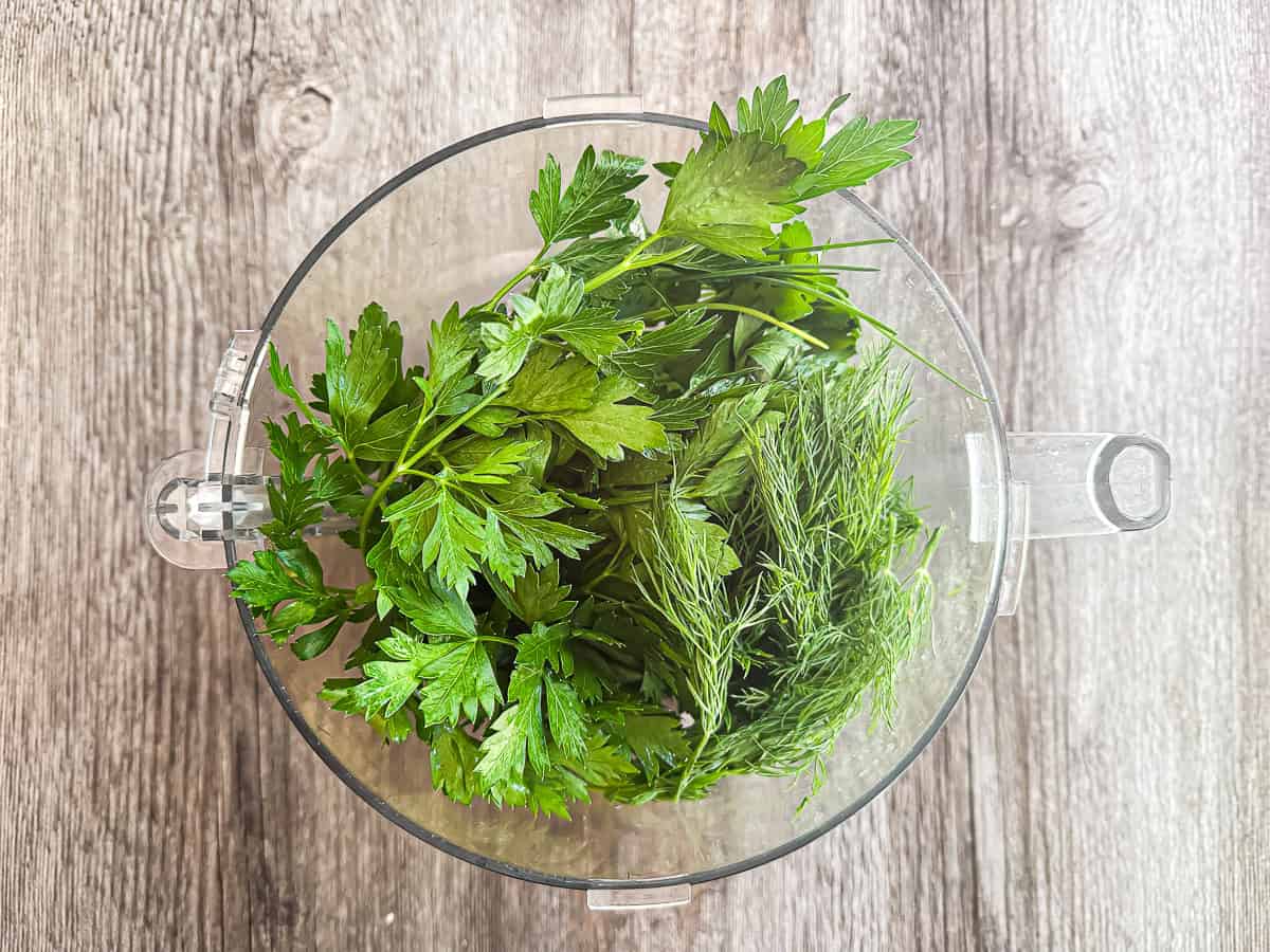 fresh herbs loaded into a food processor for easy chopping.