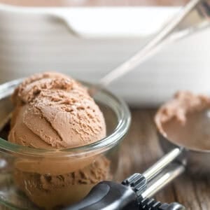 No churn Nutella ice cream in a small glass bowl, with ice cream scoop.