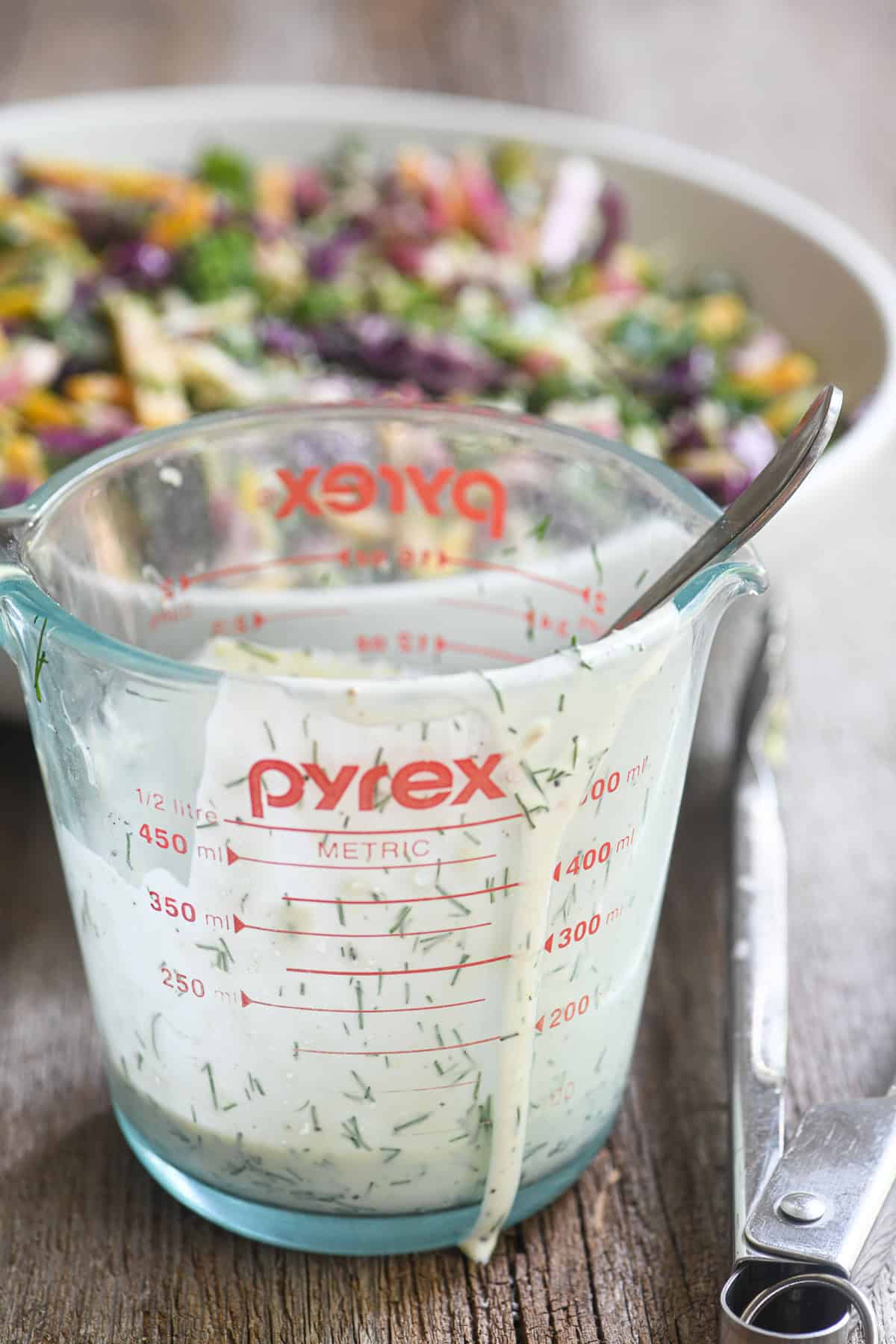 a jar of creamy lemon dill dressing in front of a bowl of power slaw.