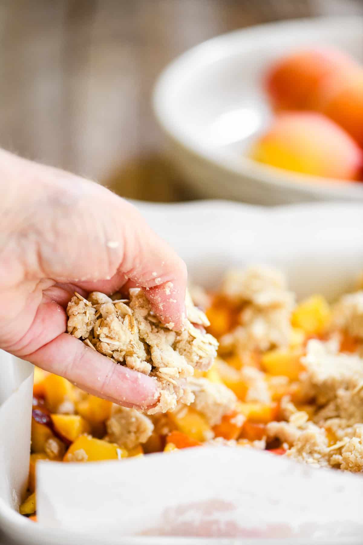 Adding cobbler topping to spiced peach cobbler bars.