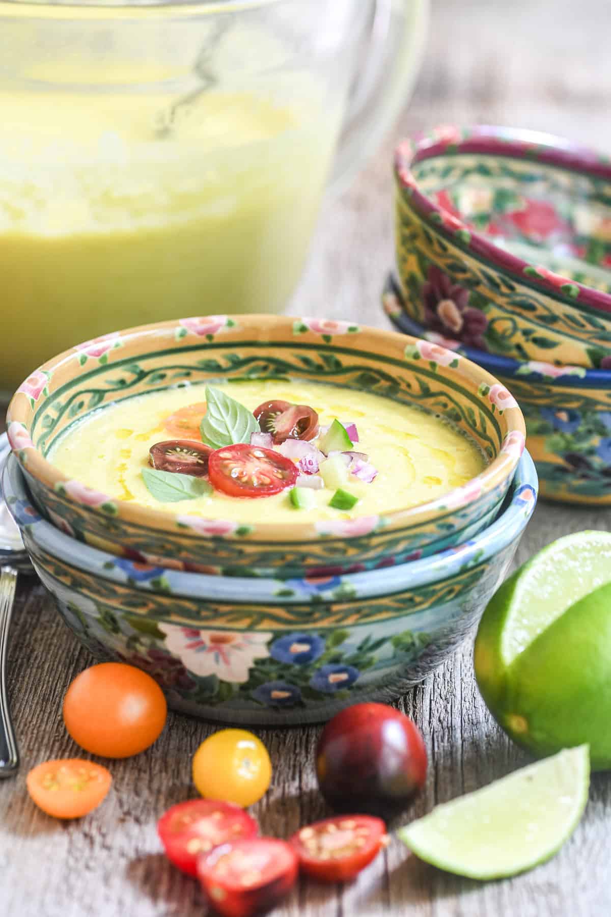 Sweet corn gazpacho in colorful bowls topped with heirloom cherry tomatoes.