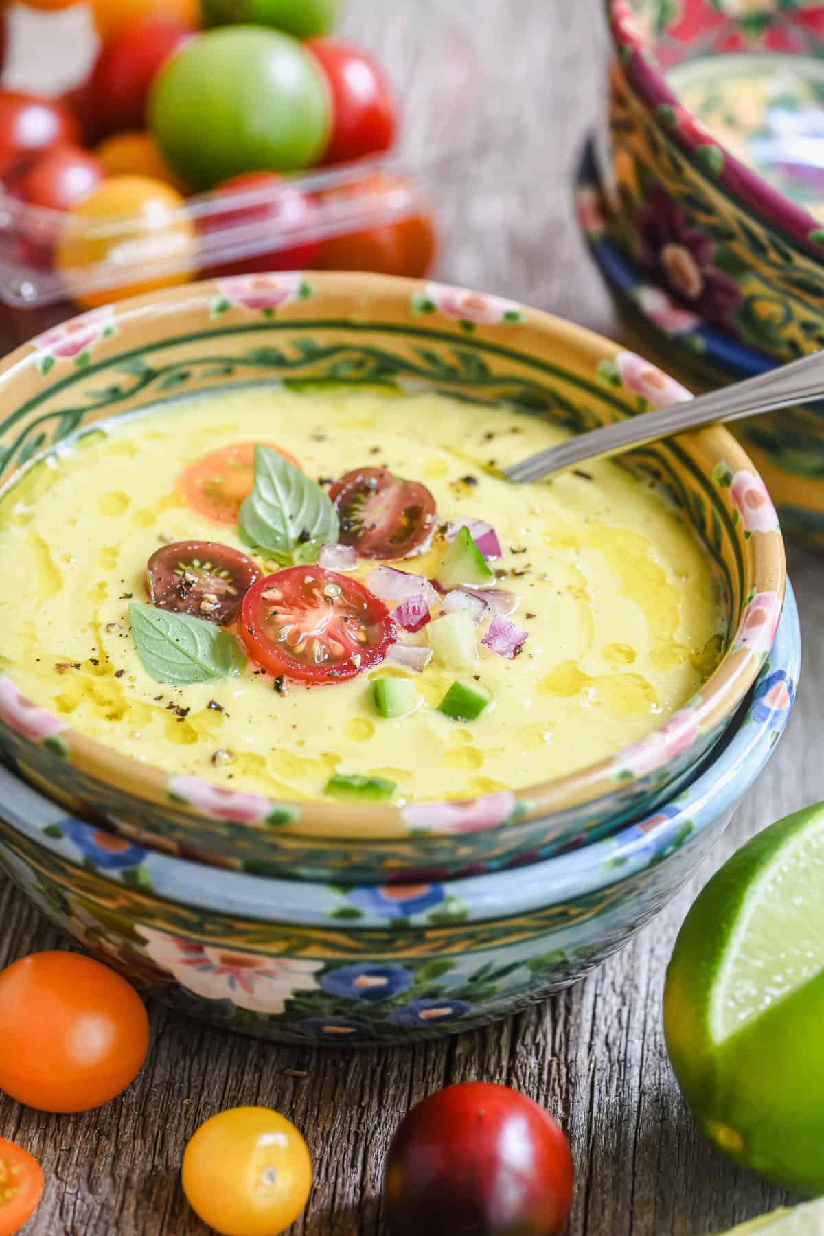 A bowl of sweet corn gazpacho topped with cherry tomatoes and basil.