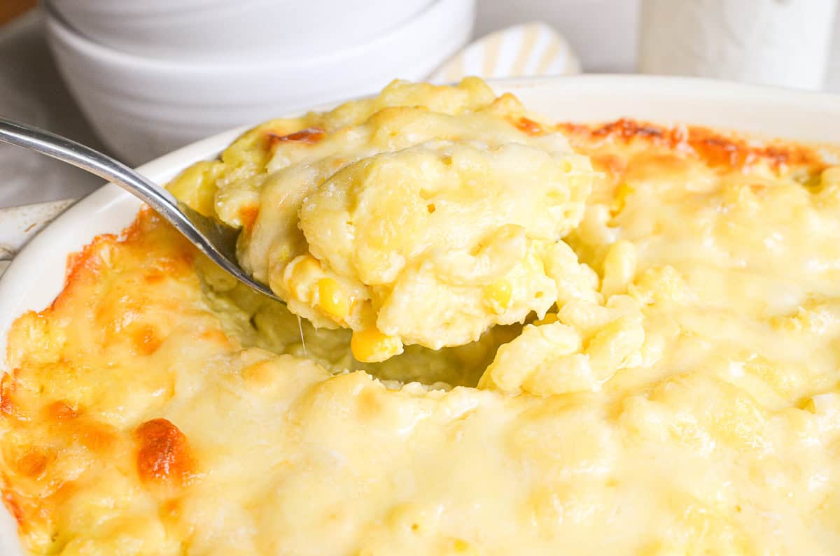 Serving sweet corn mac and cheese with a large spoon.