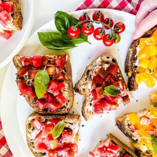 tomato toast cut into pieces, with cherry tomatoes and white plates.