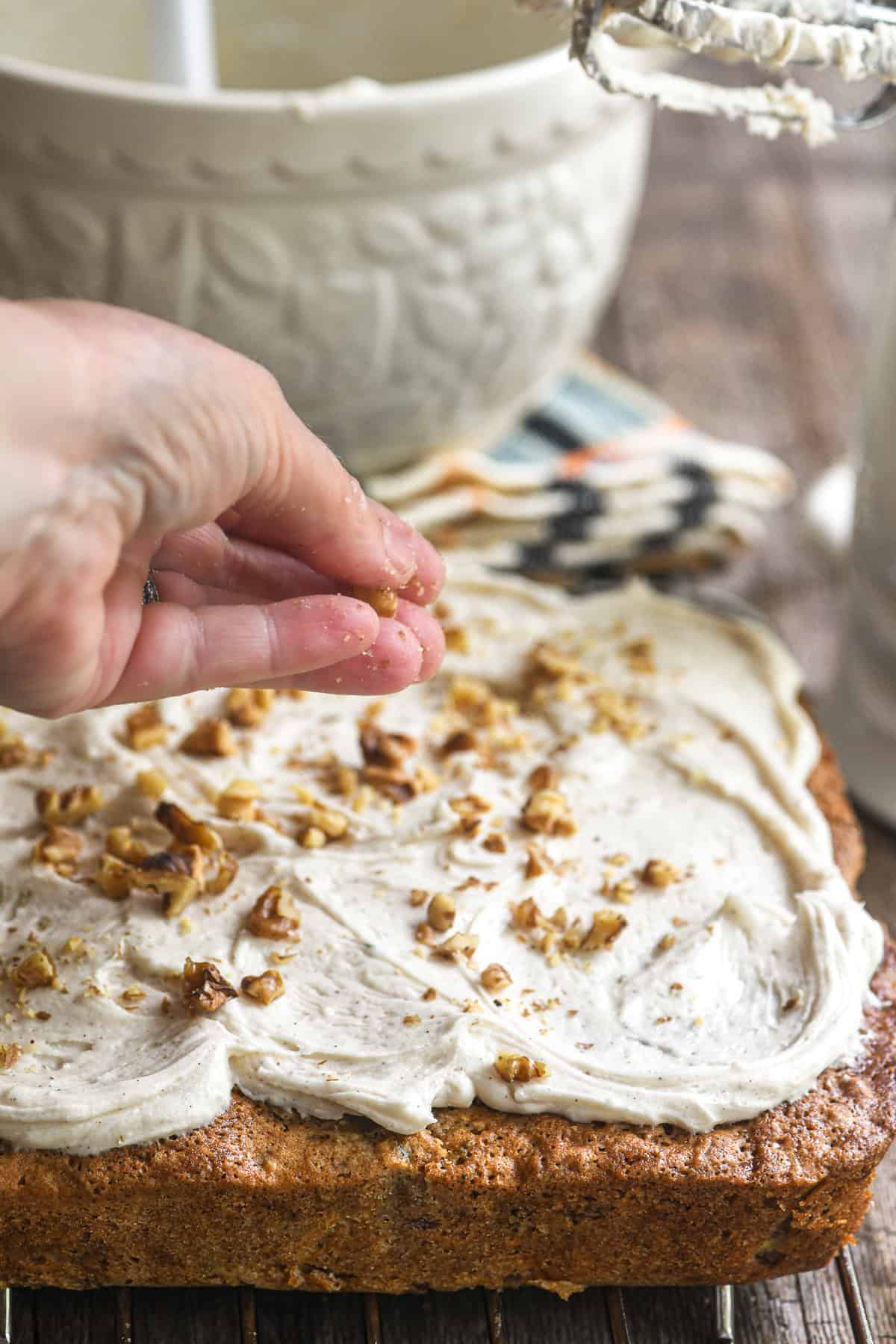 Scattering toasted walnuts on a zucchini snack cake.