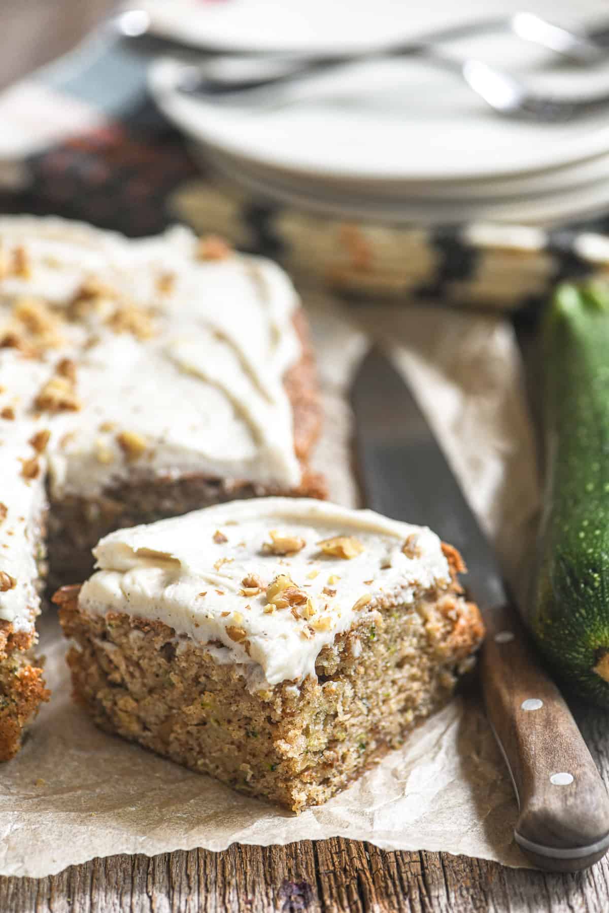 a slice of zucchini snack cake topped with browned butter frosting and toasted walnuts.