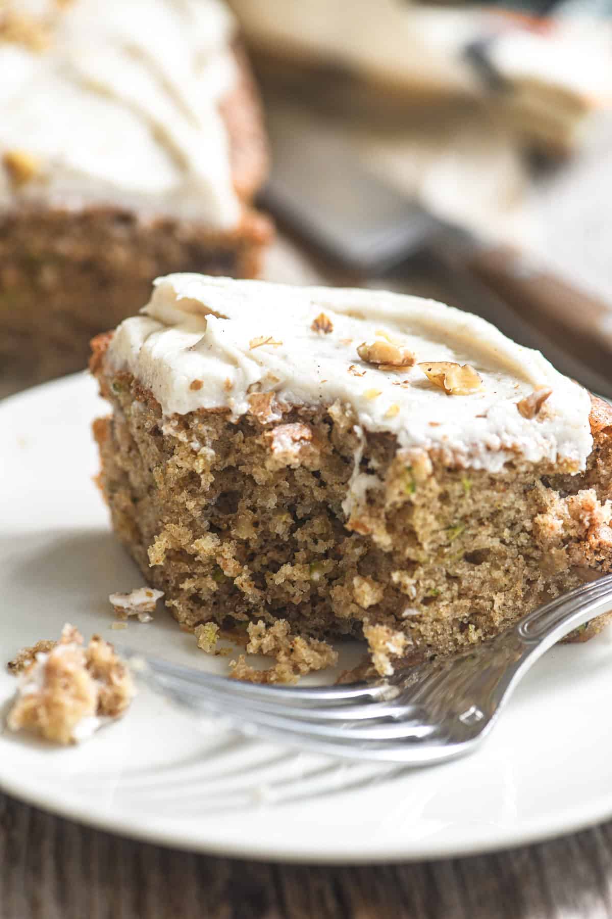 A piece of zucchini snack cake with browned butter frosting, with bite taken.