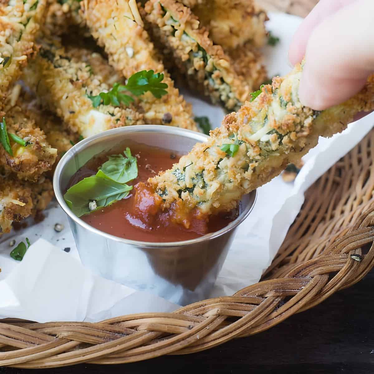 Dipping crispy zucchini fries into marinara sauce.