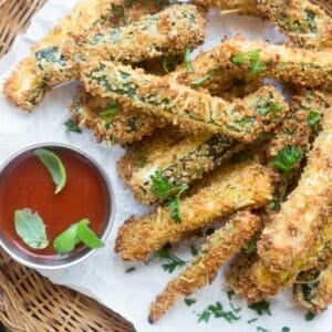 Zucchini fries on a wicker plate with marinara sauce.