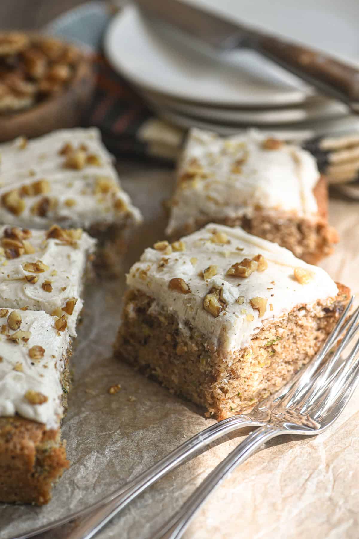 zucchini walnut snack cake topped with browned butter frosting, sliced into squares.