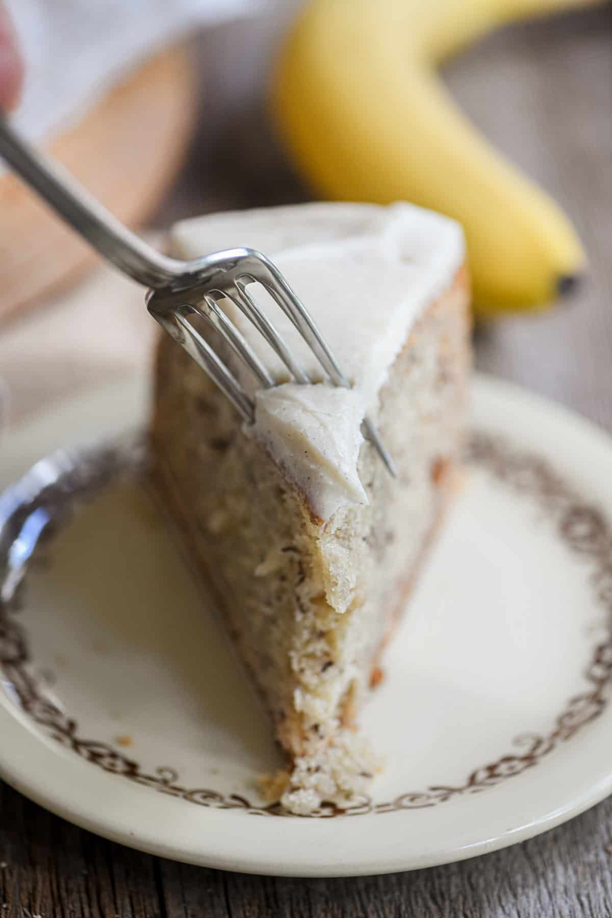 Fork going into a piece of banana cake with mascarpone frosting.