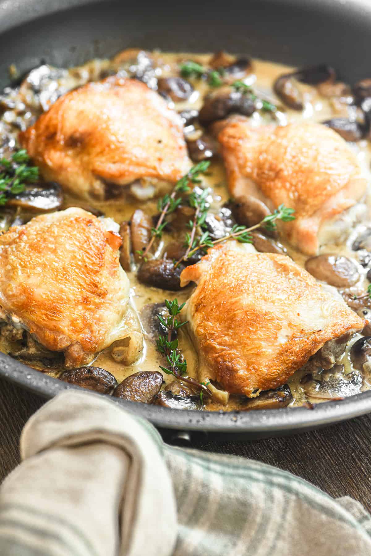 a pan of chicken thighs Marsala, just out of the oven, with kitchen towel.