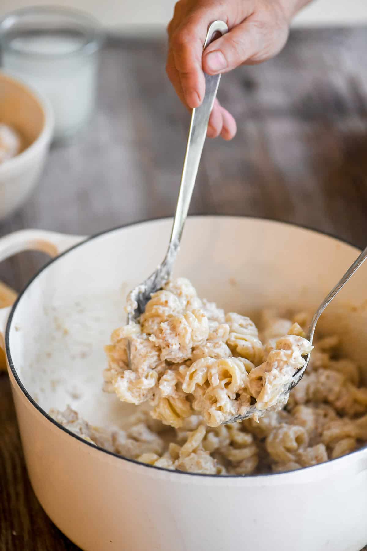 Tossing pasta with walnut sauce in a Dutch oven.