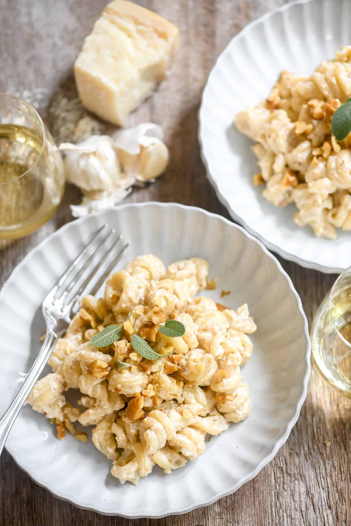 Italian pasta with walnut sauce in shallow bowls with garlic and a chunk of Parmesan.