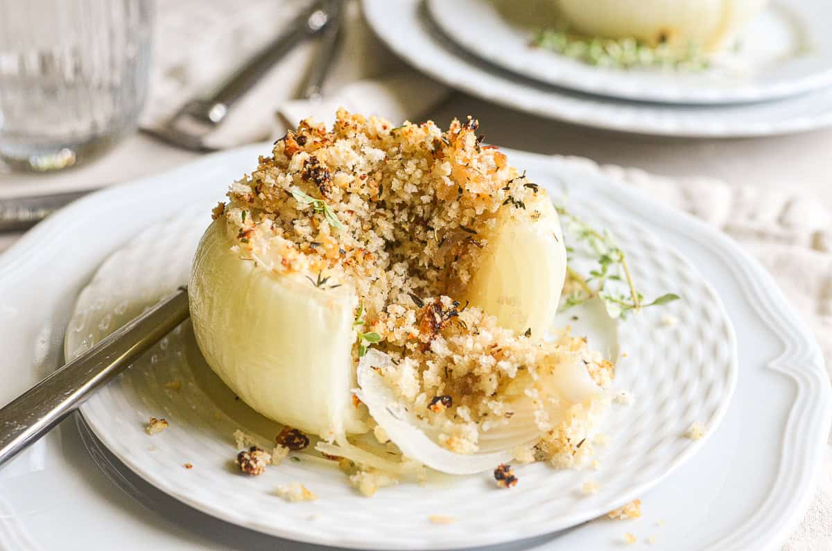 a Provencal style stuffed onion with bites taken, on a plate.