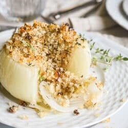 a Provencal style stuffed onion on a plate with fresh sprigs of thyme.